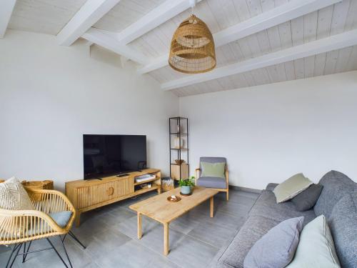 a living room with a couch and a tv at L'Épine - Maison lumineuse - 300m de la plage in LʼÉpine