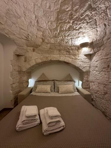 a bedroom with a bed in a stone wall at Trullo Genesi in Cisternino