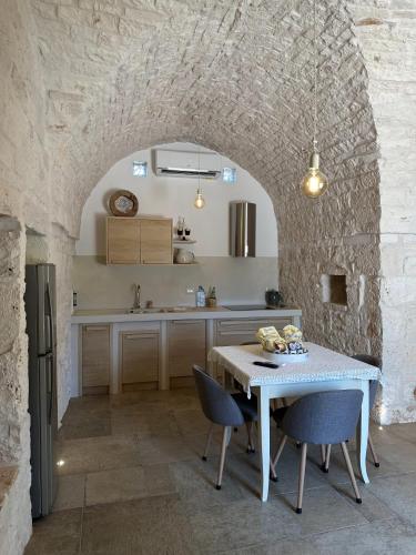 a kitchen with a table and chairs and a stone wall at Trullo Genesi in Cisternino