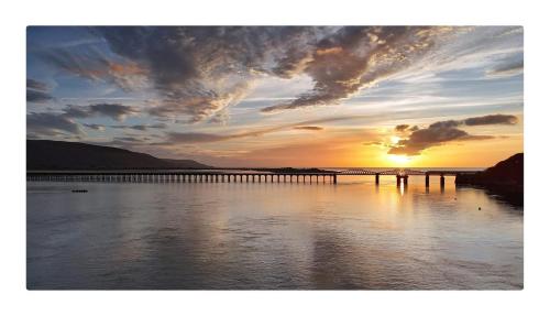 a bridge over a body of water with a sunset at The Moorings in Fairbourne
