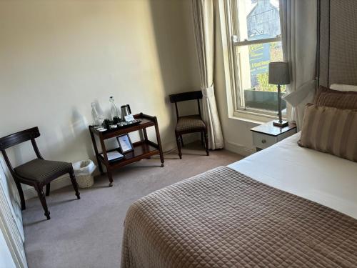 a bedroom with a bed and two chairs and a window at Horse & Hound in Delgany