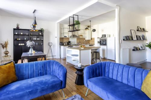 a living room with blue couches and a kitchen at Grand T3 rue piétonne bureau et terrasse in Angoulême