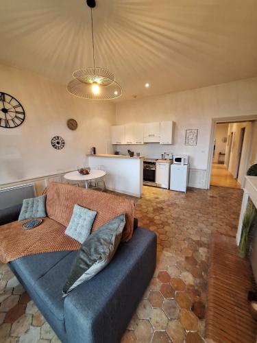 un salon avec un canapé bleu et une cuisine dans l'établissement Le Clémenceau face à la Charente 2 chambres, à Saintes
