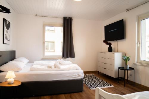 a bedroom with a bed with white sheets and a tv at homy Lakeside Symphony in Bregenz am Bodensee in Bregenz