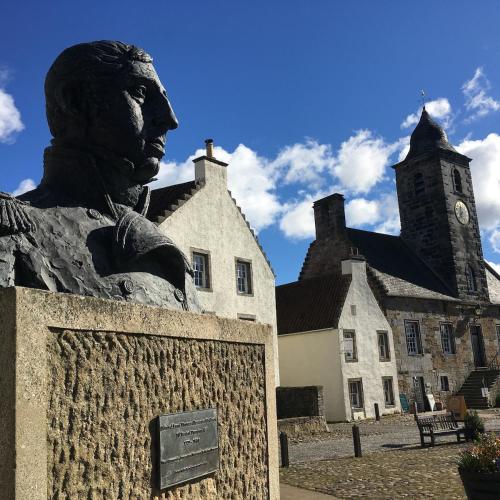 a statue in front of a building with a clock tower at A 2 Bedroom flat in Culross home of Outlander in Culross