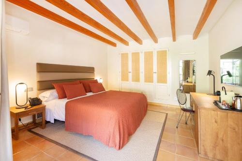 a bedroom with a bed with orange pillows in it at Hotel y Apartamentos DES PUIG in Deia