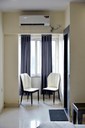 two white chairs in a room with windows at Hotel M Plaza Dhulagarh in Dhulagari
