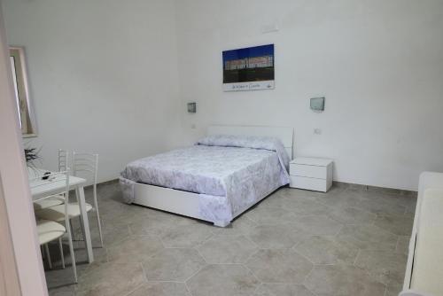 a white bedroom with a bed and a table and chairs at B&B REVOLUTION BED e BREAKFAST in Caserta
