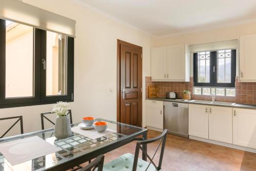 a kitchen with a glass table and chairs in a room at Saluto by Vintage Travel in Spartia