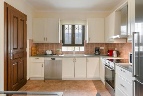 a kitchen with white cabinets and stainless steel appliances at Saluto by Vintage Travel in Spartia