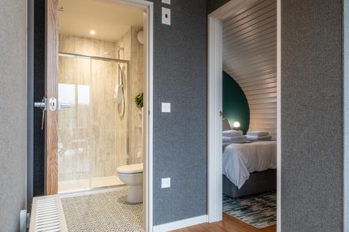 a bathroom with a shower and a toilet and a bed at Sustainable 2 Bedroom Pod on Old Chalford Farm! in Enstone