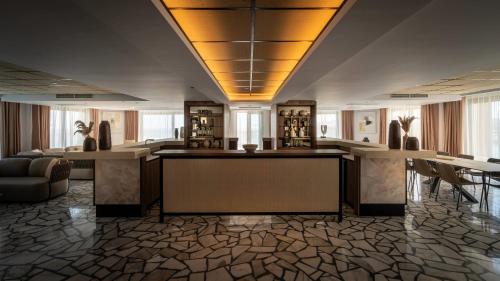 a lobby with a bar with chairs and tables at AX ODYCY Hotel in St Paul's Bay