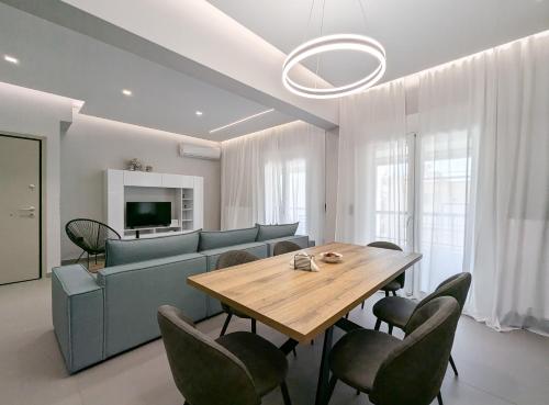 a dining room with a table and chairs and a couch at Acropolis view 3BD penthouse next to tram and port in Piraeus