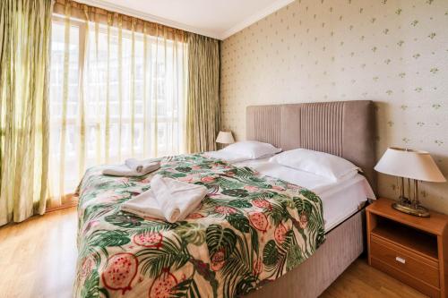 a bedroom with a large bed with a floral bedspread at ApartComplex Splendid in Saints Constantine and Helena