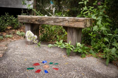 a wooden bench sitting on the ground next to flowers at The Church Accommodation in Hahei