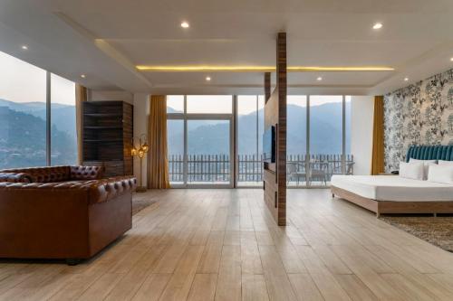 a bedroom with a bed and a couch and windows at SPT Clarks Inn Suite, Mandi in Pāndoh