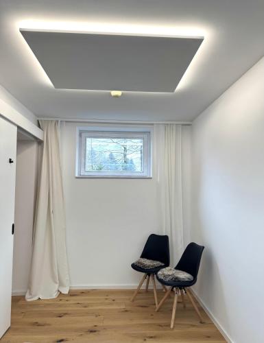 two chairs in a room with a window at Charming A&S Pohorje Apartments in Pohorje