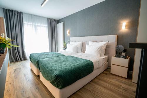 a bedroom with a large bed with a green blanket at Novos Luxury Suites in Bucharest