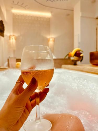a person holding a glass of wine in a bathtub at Maison LYO logement Luxe in Cannes