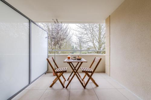 une table et des chaises sur un balcon avec une fenêtre dans l'établissement OIQIA • Palmeraie, à Bussy-Saint-Georges