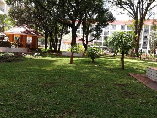 Un parque con árboles y un edificio al fondo. en Jacaranda Gardens Furnished Apartments, en Nairobi