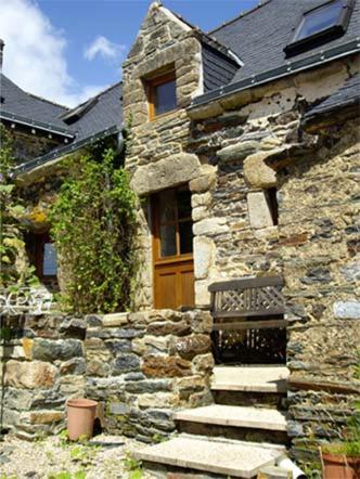 an old stone house with a wooden door and stairs at Grange Cottage in Saint-Dolay