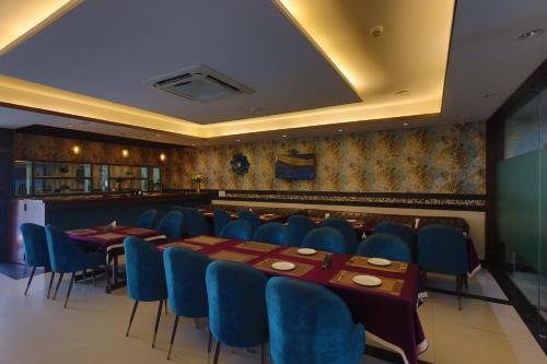 a dining room with blue chairs and a long table at Hotel The Saffron Park in Panchkula