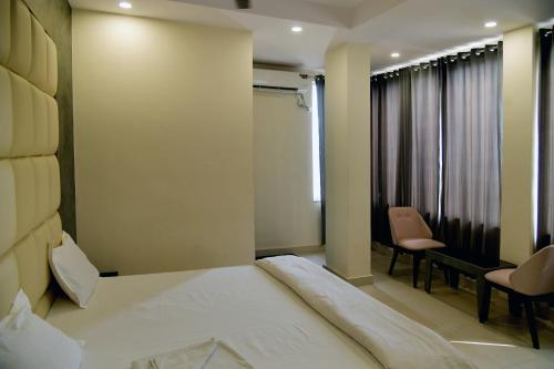 a bedroom with a bed and a chair and a window at Hotel M Plaza Dhulagarh in Dhulagari