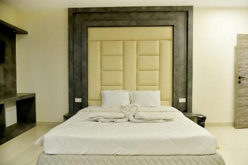 a bedroom with a large white bed with a headboard at Hotel M Plaza Dhulagarh in Dhulagari