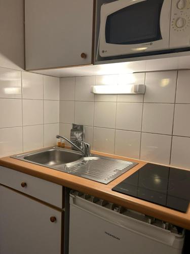 une cuisine avec un évier et un micro-ondes dans l'établissement Studio in Issy Les Moulineaux, à Issy-les-Moulineaux