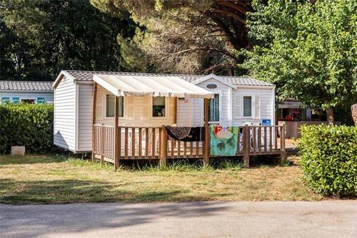 une petite maison blanche avec une clôture dans une cour dans l'établissement Mobil Home 2 chambre 4 à 6 personne en camping 4 étoiles, à Torreilles