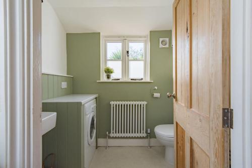 a green bathroom with a toilet and a window at Fern Cottage by Keepers Cottages in Whitstable