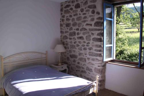 ein Schlafzimmer mit einem Bett und einer Steinwand in der Unterkunft Les Chardons Bleus in Saint-Laurent-sous-Coiron