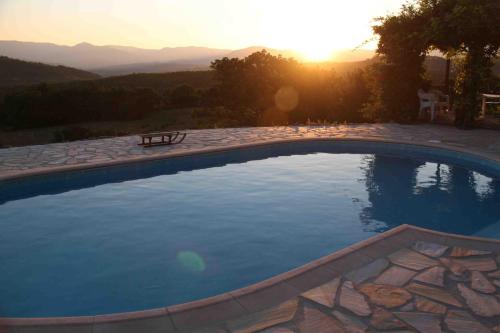 une grande piscine avec un coucher de soleil en arrière-plan dans l'établissement Les Chardons Bleus, à Saint-Laurent-sous-Coiron