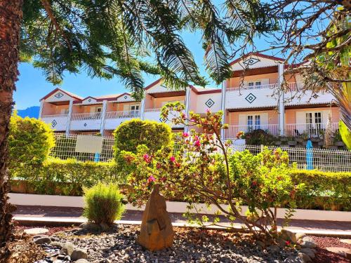 a building with a tree and flowers in front of it at Hotel Des Neiges in Cilaos