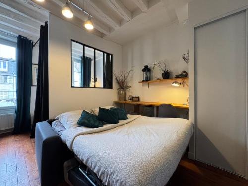 une chambre avec un lit, un bureau et une fenêtre dans l'établissement Charmant appartement en centre ville de Fontainebleau, à Fontainebleau