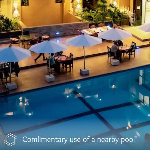 a swimming pool with tables and umbrellas in a hotel at The Nest - Newly Renovated July 2025 in Kigali