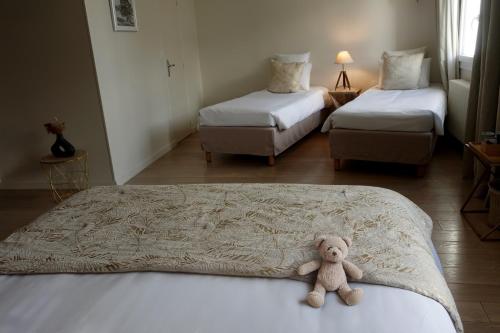 a teddy bear sitting on a bed in a room at Hôtel des Isles in Barneville-Carteret