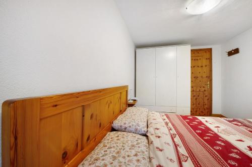 a bedroom with a bed with a wooden headboard at L'archetto Valle d'Aosta in La Salle