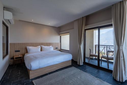 a bedroom with a large bed and a balcony at Nana Mountain Resort in Astam