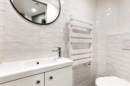 une salle de bain blanche avec un lavabo et un miroir dans l'établissement The Night Beauty - Renovated & Design - Bastille, à Paris