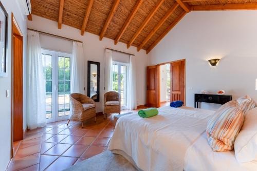 Un dormitorio con una cama grande en una habitación con ventanas. en Villa Breena - Quinta do Mar, en Almancil