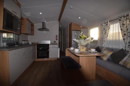 eine Küche und ein Wohnzimmer mit einer Couch und einem Tisch in der Unterkunft 25 Poplars Way Walton on Naze in Walton-on-the-Naze