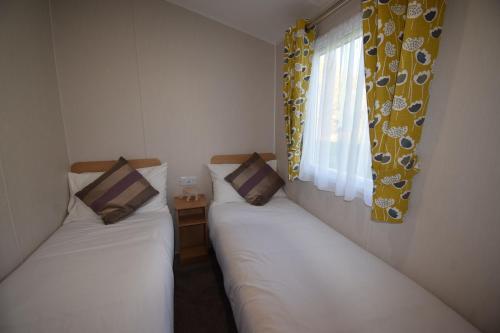 zwei Einzelbetten in einem Zimmer mit Fenster in der Unterkunft 25 Poplars Way Walton on Naze in Walton-on-the-Naze