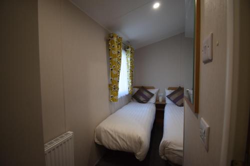 a small room with two beds and a window at 25 Poplars Way Walton on Naze in Walton-on-the-Naze