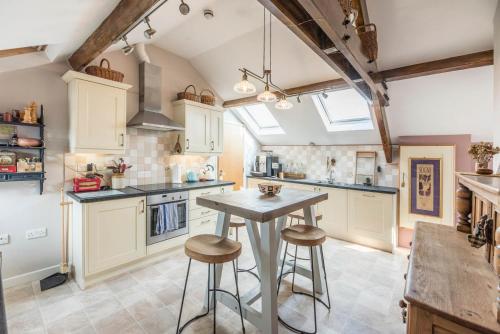 a kitchen with white cabinets and a table with stools at Ocean View, Lowestoft in Lowestoft