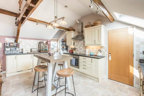 a kitchen with white cabinets and a wooden table at Ocean View, Lowestoft in Lowestoft