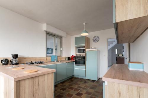 - une cuisine avec des armoires bleues et un réfrigérateur bleu dans l'établissement Maison Guidel plage - Vue mer, à Guidel