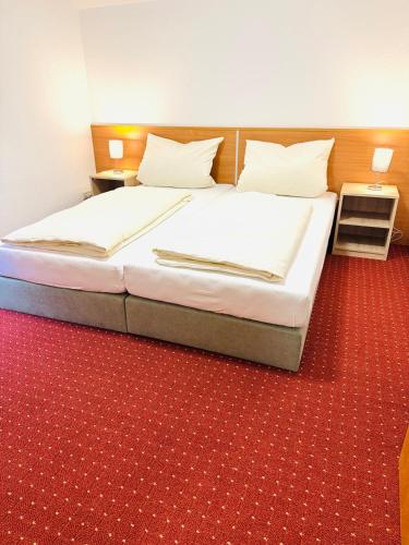 a bed in a room with a red carpet at Hotel Am Weyerhof in Kerpen