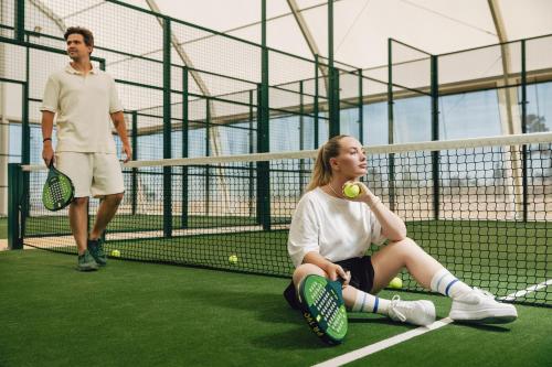 a woman sitting on a tennis court with a tennis ball at Royal Obidos Scenic Resort in Casal da Lagoa Seca
